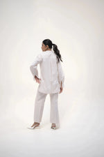 Load image into Gallery viewer, The model in a white shirt and trousers, striking a confident pose with one hand resting on her hip, facing the camera.