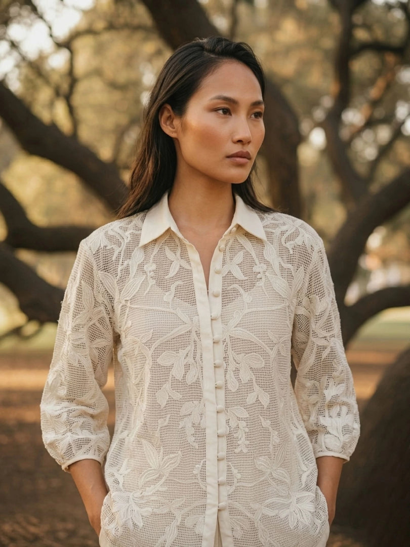 Woman wearing ivory openwork crochet summer lace shirt with floral embroidery, front close-up view, lightweight white lace blouse for women.