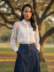 Women’s white button-down shirt paired with wide-leg navy trousers, elegant casual outfit front view.