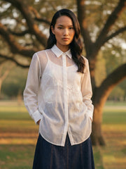 Lightweight white resort blouse with navy pants, full-length summer fashion look for women.