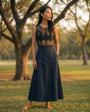 Sheer black organza top with floral embroidery styled outdoors. Lightweight fabric with a soft flow, perfect for festive and evening wear looks.